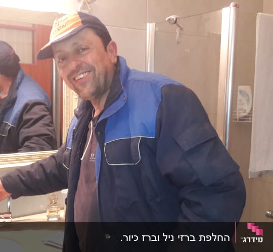 אדם עם כובע מתקין ברז בחדר אמבטיה